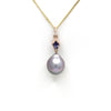Pearl in 14k pendant with a blue gemstone on a gold chain against a white background